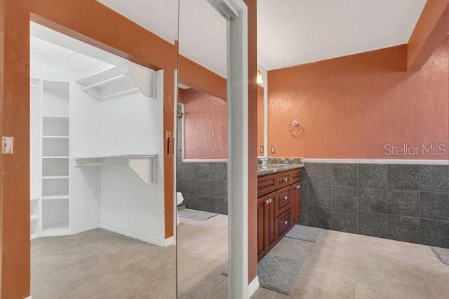 9319 Woodbreeze Blvd, Windermere, FL 34786 - full bathroom with vanity, tile walls, tile patterned flooring, and a walk in closet