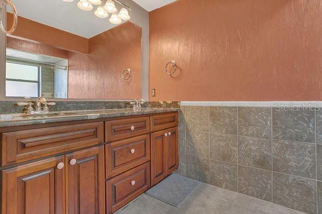 9319 Woodbreeze Blvd, Windermere, FL 34786 - full bath with double vanity, a wainscoted wall, tile patterned floors, and tile walls