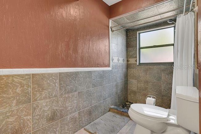 9319 Woodbreeze Blvd, Windermere, FL 34786 - bathroom featuring toilet, a tile shower, and tile walls