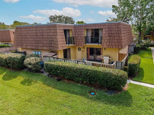 5287 Cypress Ct Unit 724, Orlando, FL 32811 - back of house with mansard roof, a balcony, a lawn, and brick siding