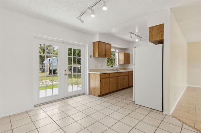 325 Little Aspen Ct, Ocoee, FL 34761 - kitchen featuring freestanding refrigerator, rail lighting, light countertops, french doors, and brown cabinets