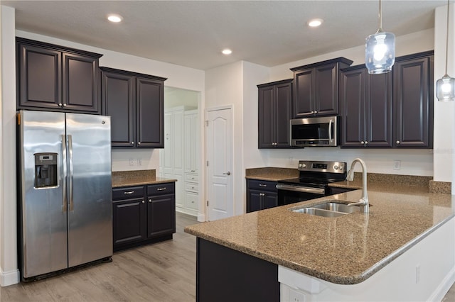 15229 Evergreen Oak Loop, Winter Garden, FL 34787 - kitchen featuring appliances with stainless steel finishes, dark stone counters, a peninsula, light wood-type flooring, and pendant lighting