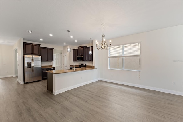 15229 Evergreen Oak Loop, Winter Garden, FL 34787 - kitchen featuring appliances with stainless steel finishes, a chandelier, light wood-type flooring, dark brown cabinetry, and recessed lighting