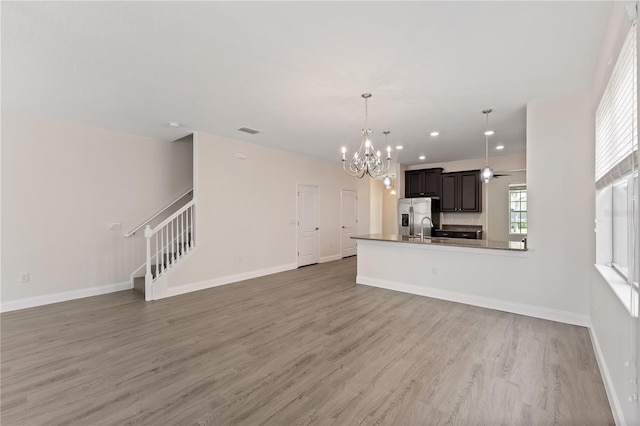 15229 Evergreen Oak Loop, Winter Garden, FL 34787 - unfurnished living room with a chandelier, stairway, light wood-style floors, a sink, and baseboards