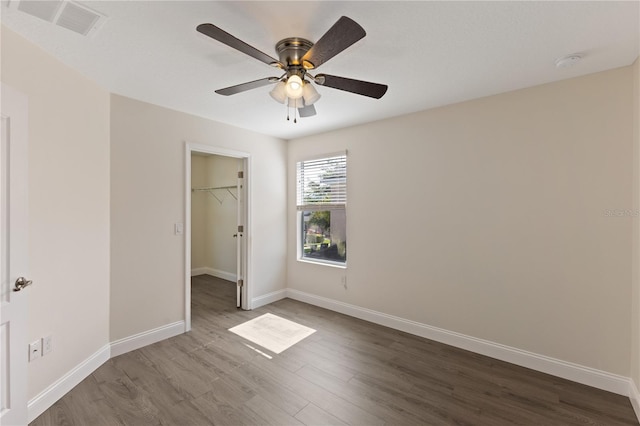 15229 Evergreen Oak Loop, Winter Garden, FL 34787 - unfurnished bedroom featuring dark wood finished floors, a walk in closet, and baseboards