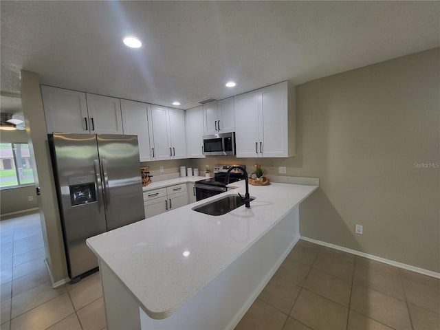 4883 Cherokee Rose Dr, Orlando, FL 32808 - kitchen with stainless steel appliances, a peninsula, recessed lighting, light tile patterned floors, and white cabinetry