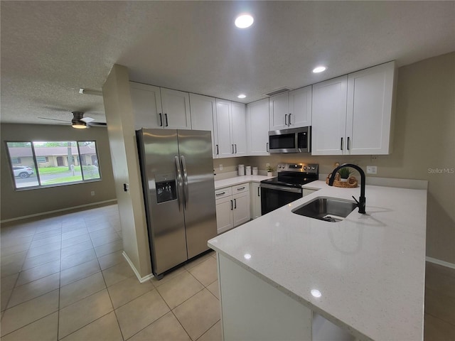4883 Cherokee Rose Dr, Orlando, FL 32808 - kitchen with appliances with stainless steel finishes, a sink, a peninsula, white cabinetry, and baseboards