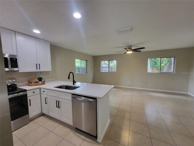 4883 Cherokee Rose Dr, Orlando, FL 32808 - kitchen featuring appliances with stainless steel finishes, a peninsula, light countertops, open floor plan, and white cabinetry