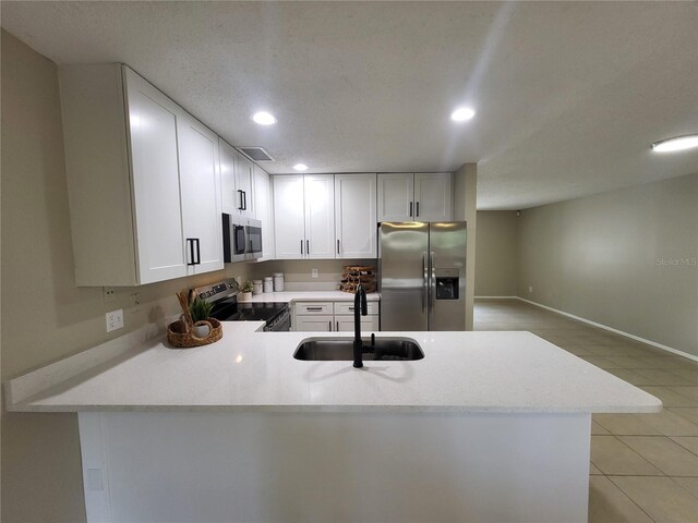 4883 Cherokee Rose Dr, Orlando, FL 32808 - kitchen with stainless steel appliances, recessed lighting, light tile patterned floors, a peninsula, and white cabinets
