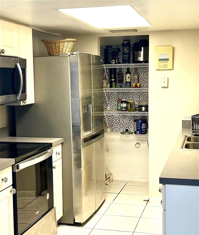 1815 Townhall Ln Unit 1815, Orlando, FL 32807 - kitchen with stainless steel microwave, electric range, light tile patterned floors, white cabinetry, and a sink