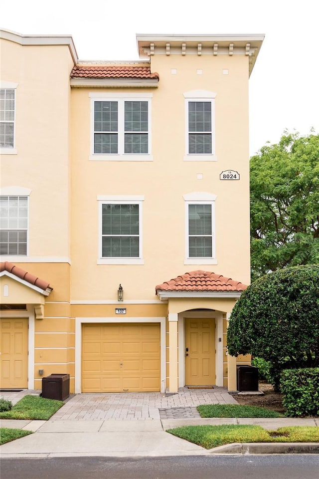 8024 Cool Breeze Dr Unit 132, Orlando, FL 32819 - view of front of property with stucco siding, a tiled roof, an attached garage, and driveway