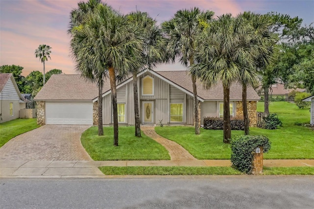 526 Sabal Trail Cir, Longwood, FL 32779 - mid-century home featuring stone siding, driveway, a lawn, an attached garage, and roof with shingles