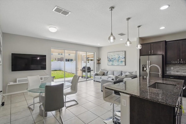 914 Fallon Hills Dr, Haines City, FL 33844 - kitchen with stainless steel refrigerator with ice dispenser, open floor plan, a sink, dark brown cabinets, and a kitchen breakfast bar
