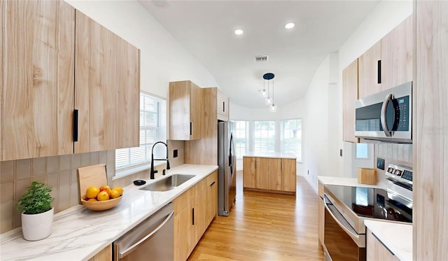 10747 Satinwood Cir, Orlando, FL 32825 - kitchen with appliances with stainless steel finishes, modern cabinets, a sink, light brown cabinets, and decorative backsplash