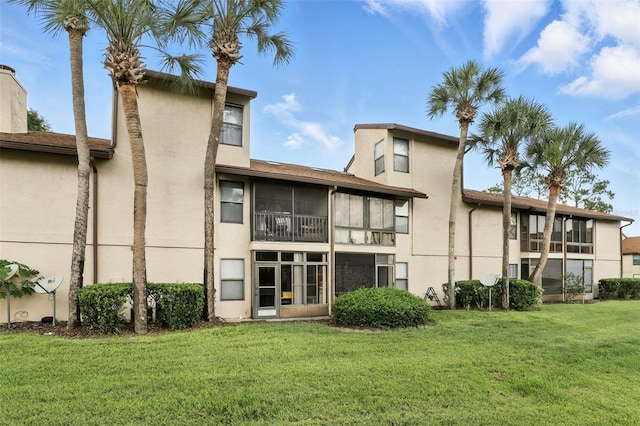 3012 S Semoran Blvd Unit S, Orlando, FL 32822 - rear view of house featuring stucco siding, a lawn, and a sunroom