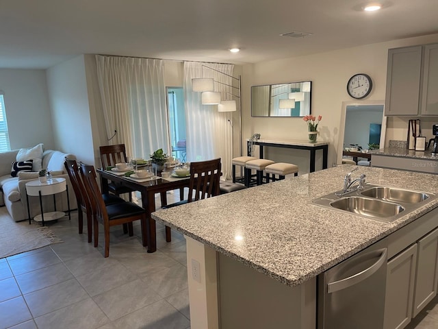 7172 SW 135th Pl, Ocala, FL 34473 - kitchen with dishwasher, gray cabinetry, light tile patterned floors, a kitchen island with sink, and light stone countertops