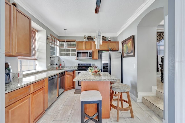 2971 Cayman Way, Orlando, FL 32812 - kitchen with stainless steel appliances, a sink, a kitchen island, light stone counters, and ornamental molding