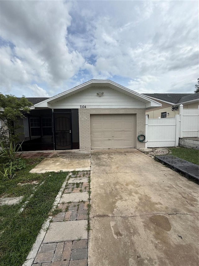 7104 Blue Earth Ct, Orlando, FL 32818 - view of front of house with an attached garage, brick siding, driveway, and a sunroom