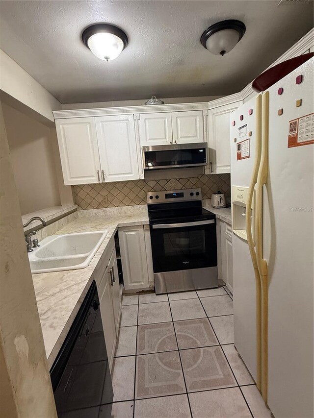 7104 Blue Earth Ct, Orlando, FL 32818 - kitchen with stainless steel appliances, decorative backsplash, light countertops, white cabinets, and a textured ceiling