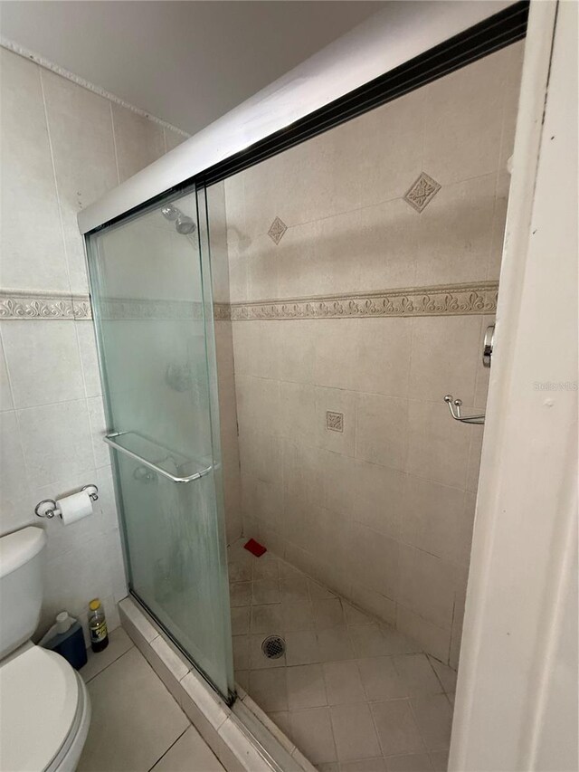 7104 Blue Earth Ct, Orlando, FL 32818 - bathroom with tile walls, toilet, a stall shower, and tile patterned flooring