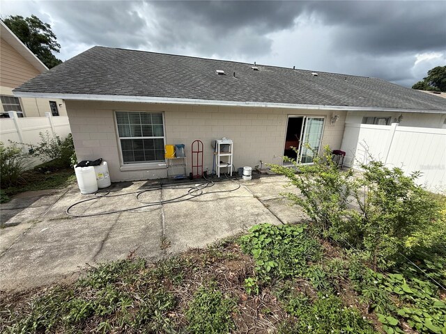 7104 Blue Earth Ct, Orlando, FL 32818 - back of property with a shingled roof, concrete block siding, and a patio