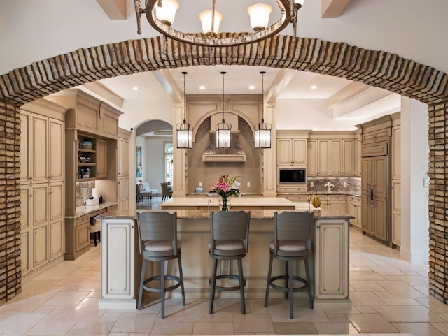 11106 Coniston Way, Windermere, FL 34786 - kitchen with built in appliances, a large island with sink, arched walkways, light stone countertops, and stone tile floors