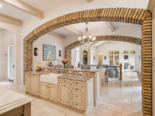 11106 Coniston Way, Windermere, FL 34786 - kitchen with cream cabinetry, a sink, stone tile flooring, arched walkways, and beam ceiling