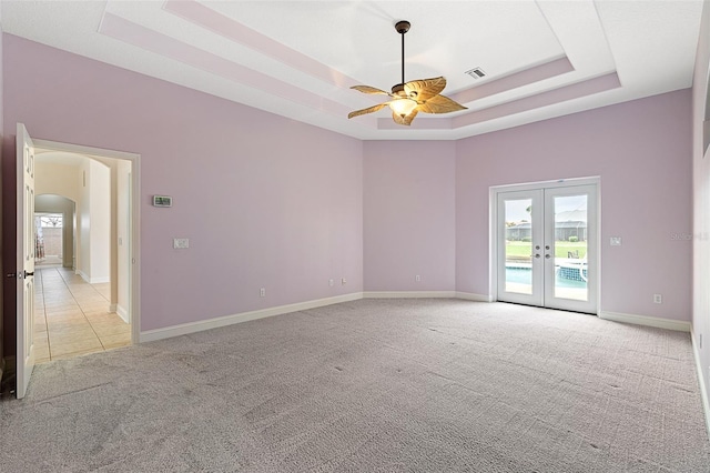 5 Florence Ct, Palm Coast, FL 32137 - spare room featuring light carpet, a tray ceiling, ceiling fan, arched walkways, and french doors