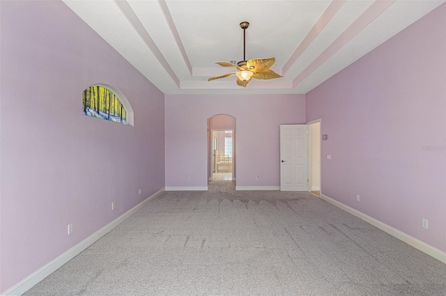 5 Florence Ct, Palm Coast, FL 32137 - empty room with arched walkways, a tray ceiling, ceiling fan, carpet, and healthy amount of natural light