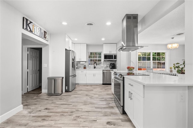 3251 Wickersham Ct, Orlando, FL 32806 - kitchen featuring appliances with stainless steel finishes, island exhaust hood, backsplash, white cabinets, and recessed lighting