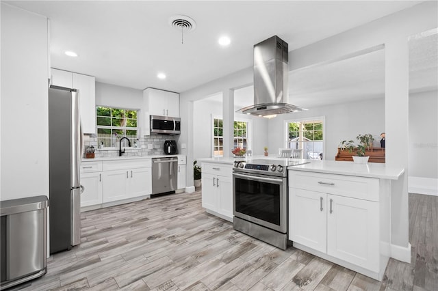 3251 Wickersham Ct, Orlando, FL 32806 - kitchen with appliances with stainless steel finishes, island exhaust hood, light countertops, light wood-style floors, and recessed lighting
