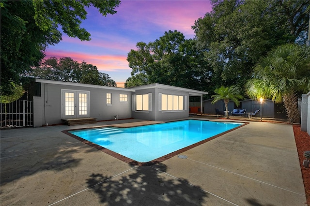 3251 Wickersham Ct, Orlando, FL 32806 - pool at dusk with french doors, a patio area, and an outdoor structure