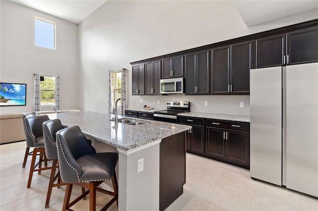 5639 Timber Meadow Way, Saint Cloud, FL 34771 - kitchen featuring stainless steel appliances, a towering ceiling, light tile patterned flooring, plenty of natural light, and an island with sink