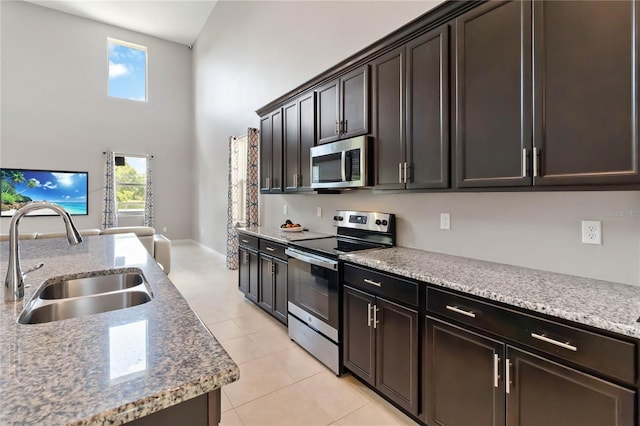 5639 Timber Meadow Way, Saint Cloud, FL 34771 - kitchen with appliances with stainless steel finishes, a towering ceiling, light tile patterned floors, light stone countertops, and dark brown cabinets
