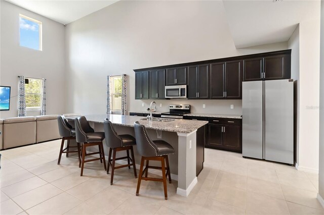 5639 Timber Meadow Way, Saint Cloud, FL 34771 - kitchen featuring appliances with stainless steel finishes, a towering ceiling, a breakfast bar area, plenty of natural light, and an island with sink