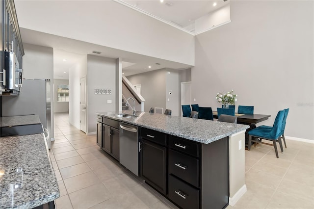 5639 Timber Meadow Way, Saint Cloud, FL 34771 - kitchen featuring appliances with stainless steel finishes, light tile patterned floors, a kitchen island with sink, and light stone counters