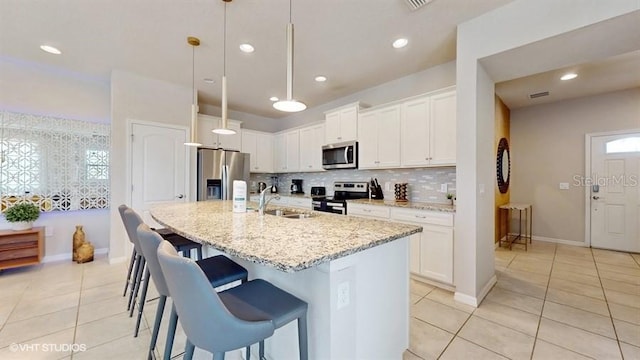 8900 Sydney Ave, Kissimmee, FL 34747 - kitchen featuring stainless steel appliances, light tile patterned flooring, a center island with sink, light stone counters, and a kitchen bar