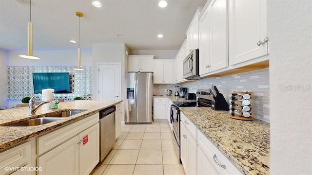 8900 Sydney Ave, Kissimmee, FL 34747 - kitchen with stainless steel appliances, decorative backsplash, white cabinets, light stone countertops, and pendant lighting