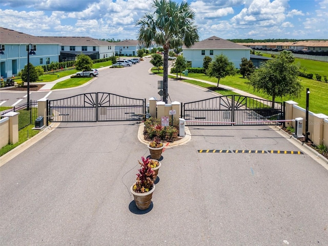 8900 Sydney Ave, Kissimmee, FL 34747 - view of asphalt street featuring a gate, curbs, a gated entry, a residential view, and sidewalks