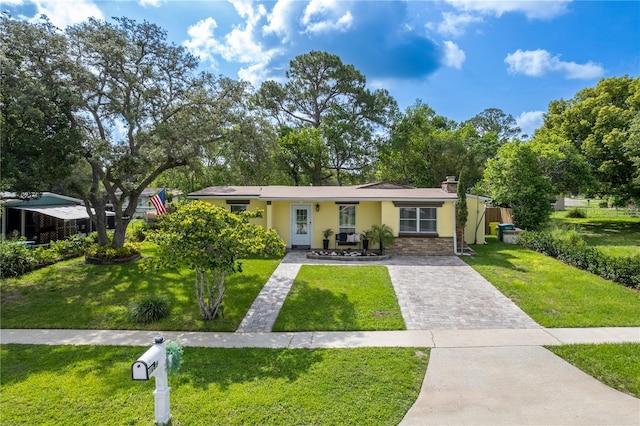 1649 W Waycross Cir, Deltona, FL 32725 - view of front of house featuring stucco siding, a front yard, driveway, stone siding, and a chimney