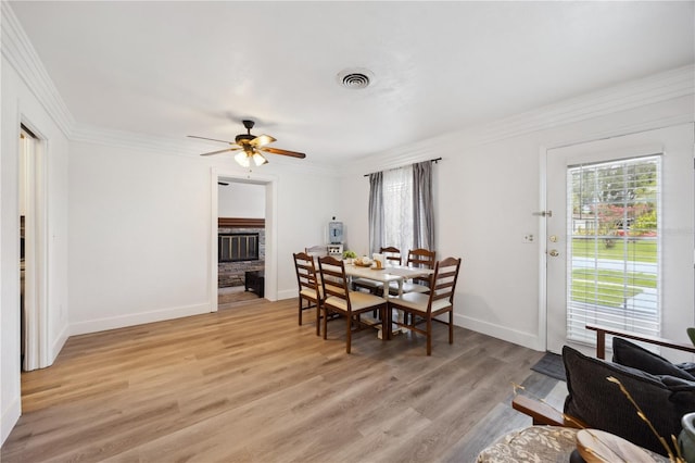 1649 W Waycross Cir, Deltona, FL 32725 - dining area with a fireplace with raised hearth, crown molding, ceiling fan, light wood-style floors, and baseboards