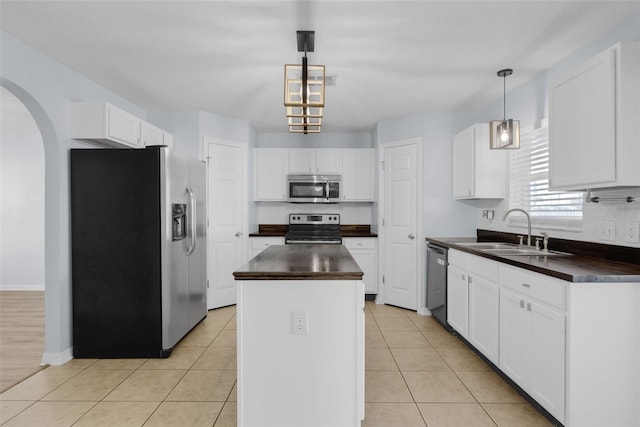 2255 Tealwood Cir, Tavares, FL 32778 - kitchen with stainless steel appliances, a sink, dark countertops, arched walkways, and a kitchen island