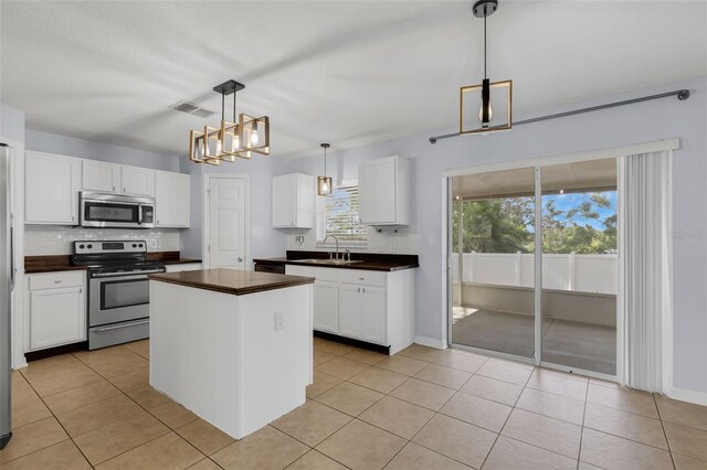 2255 Tealwood Cir, Tavares, FL 32778 - kitchen with stainless steel appliances, dark countertops, a sink, and white cabinetry