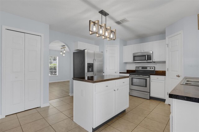 2255 Tealwood Cir, Tavares, FL 32778 - kitchen with stainless steel appliances, dark countertops, arched walkways, a chandelier, and white cabinetry