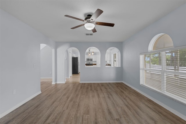 2255 Tealwood Cir, Tavares, FL 32778 - empty room with a ceiling fan, wood finished floors, arched walkways, and baseboards