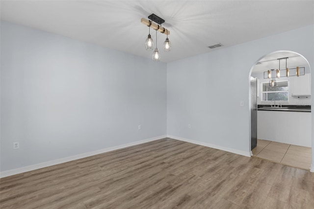 2255 Tealwood Cir, Tavares, FL 32778 - unfurnished room with a sink, light wood-style flooring, arched walkways, and baseboards