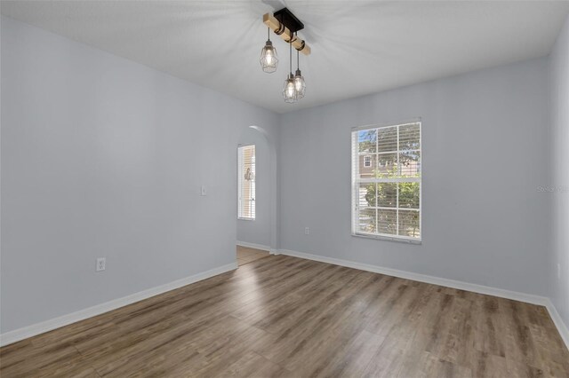 2255 Tealwood Cir, Tavares, FL 32778 - unfurnished room featuring arched walkways, wood finished floors, and baseboards