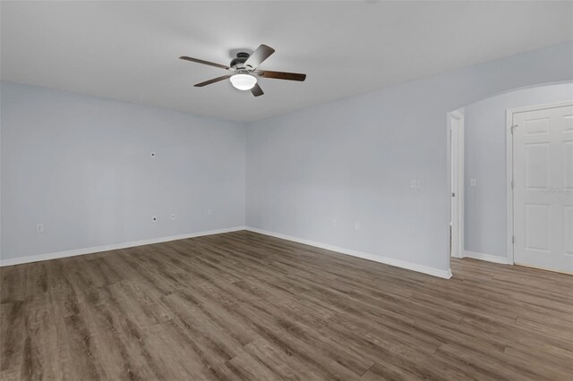 2255 Tealwood Cir, Tavares, FL 32778 - empty room with a ceiling fan, wood finished floors, arched walkways, and baseboards