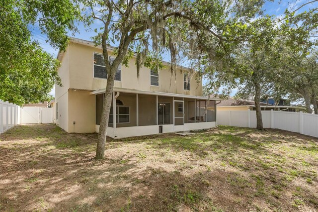 2255 Tealwood Cir, Tavares, FL 32778 - rear view of property with a sunroom, a fenced backyard, a gate, and stucco siding