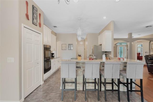1031 Kings Hwy, Kissimmee, FL 34744 - kitchen featuring arched walkways, freestanding refrigerator, a kitchen breakfast bar, and white cabinetry